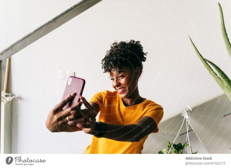 Laughing black woman taking selfie with smartphone at home using laugh having fun excited browsing mobile cheerful millennial young adolescent female modern