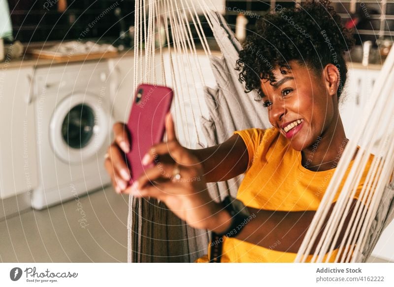 Ethnic young woman taking selfie at home smartphone cheerful share mobile smile carefree positive female student african american black ethnic millennial