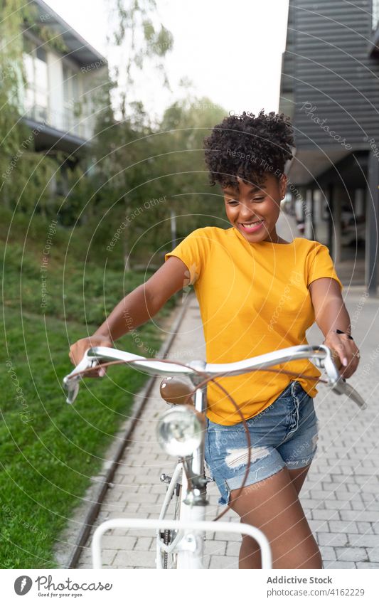 Positive black woman riding bicycle on street bike ride happy activity summer urban trendy positive young female african american ethnic millennial teenage