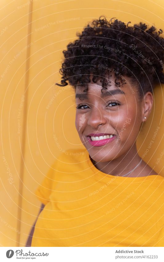 Cheerful black woman in bright outfit happy cheerful colorful smile yellow style positive confident young african american ethnic afro casual modern curly hair