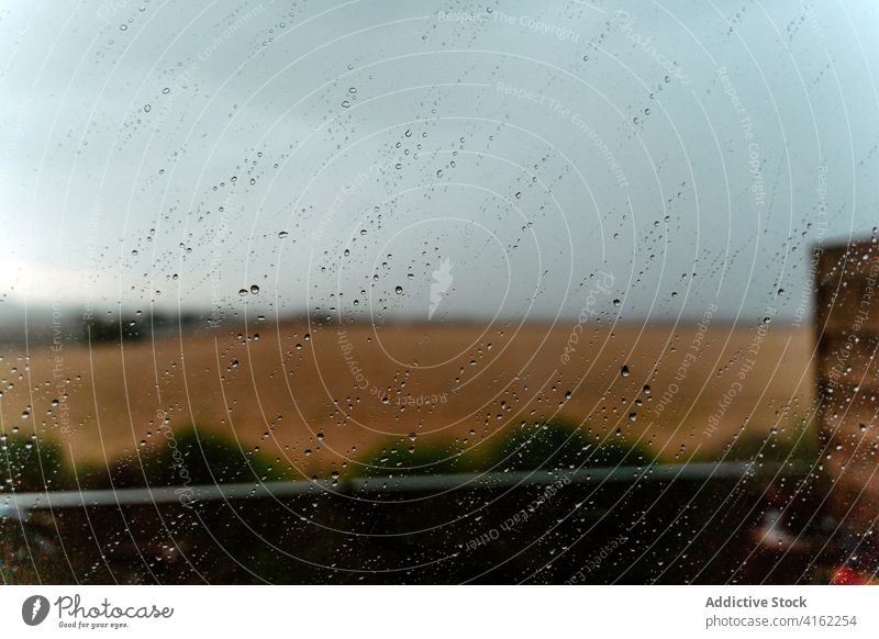 Rain drops on window in countryside glass rain meadow condense nature overcast field tranquil calm rural droplet water daytime wet drip idyllic serene grass