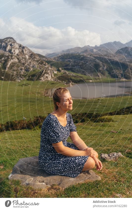 Woman resting on stone against spectacular mountainous valley woman highland magnificent admire terrain pond landscape range lake scenery hillside nature