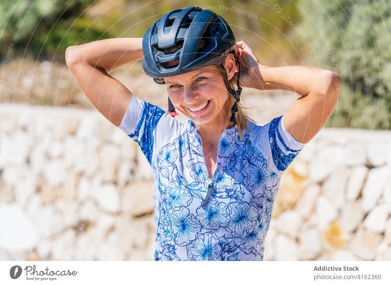 Cheerful woman putting on bike helmet cyclist active happy prepare sporty bicyclist protect cheerful ride young female laugh safety lifestyle smile put on