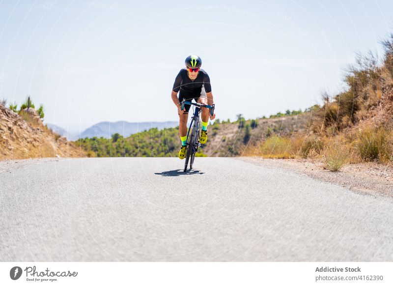 Cyclist riding bike on rural road in highlands cyclist ride mountain bicycle active sport route workout nature man lifestyle activity healthy summer adventure