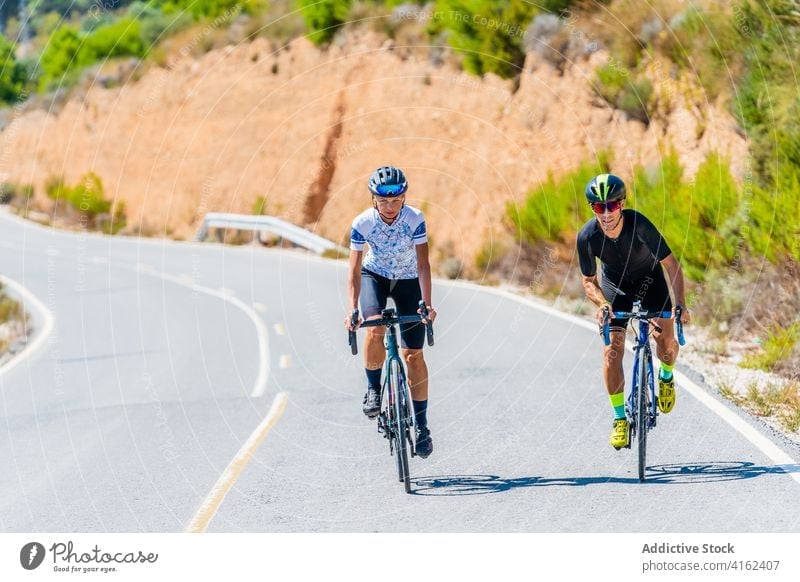 Active couple riding bicycles on country road cyclist bike ride point away active together nature lifestyle sport activity healthy summer adventure direction