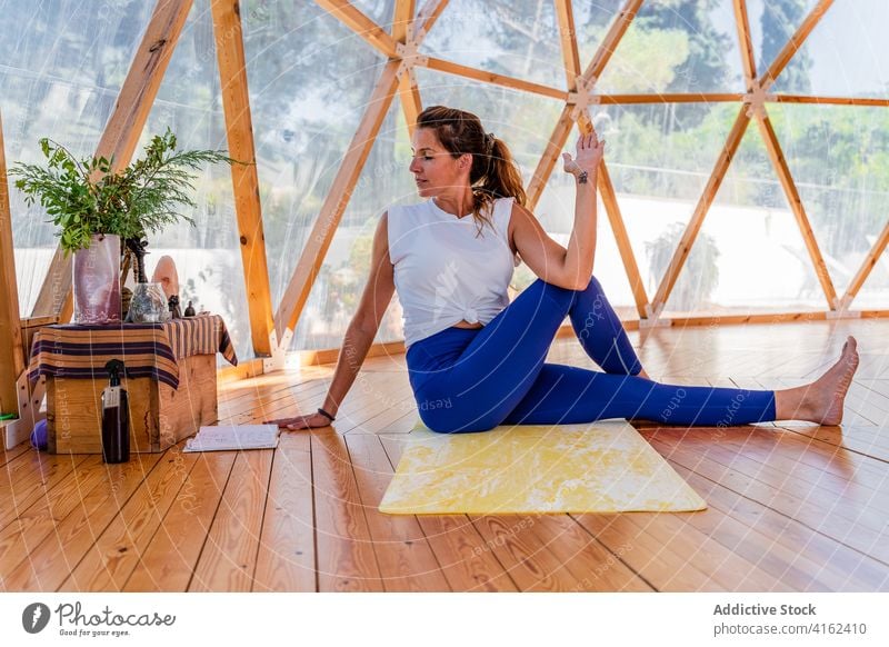 Unrecognizable woman standing in marichi's pose yoga practice flexible balance healthy lifestyle wellness mat barefoot Marichyasana tattoo fit sit arm raised