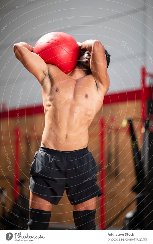 Determined ethnic sportsman with fitness ball during training in gym athlete muscle workout determine focus exercise functional muscular strong