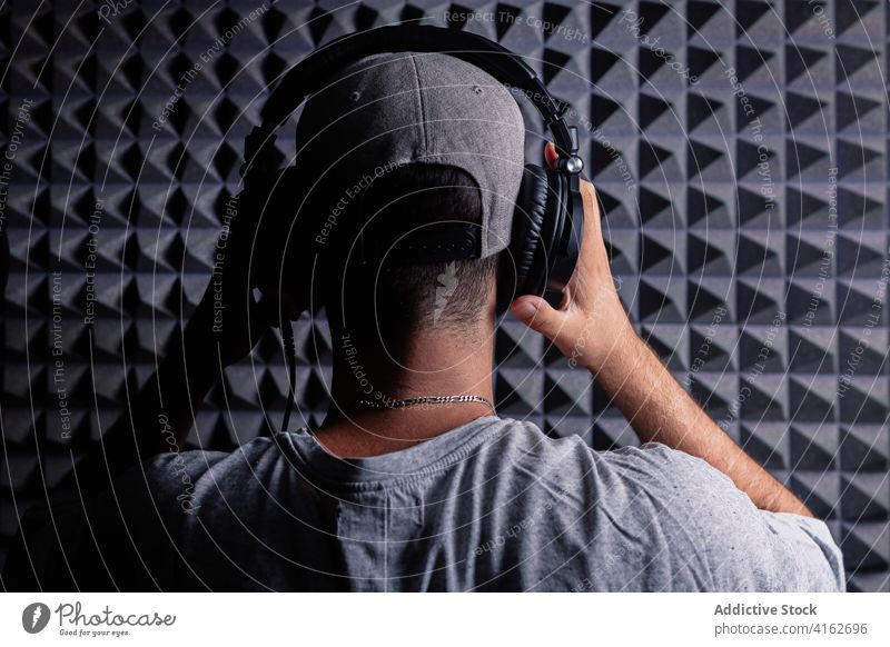 Anonymous man in headphones in recording studio sound proof music singer artist foam room male acoustic panel contemporary device modern confident equipment