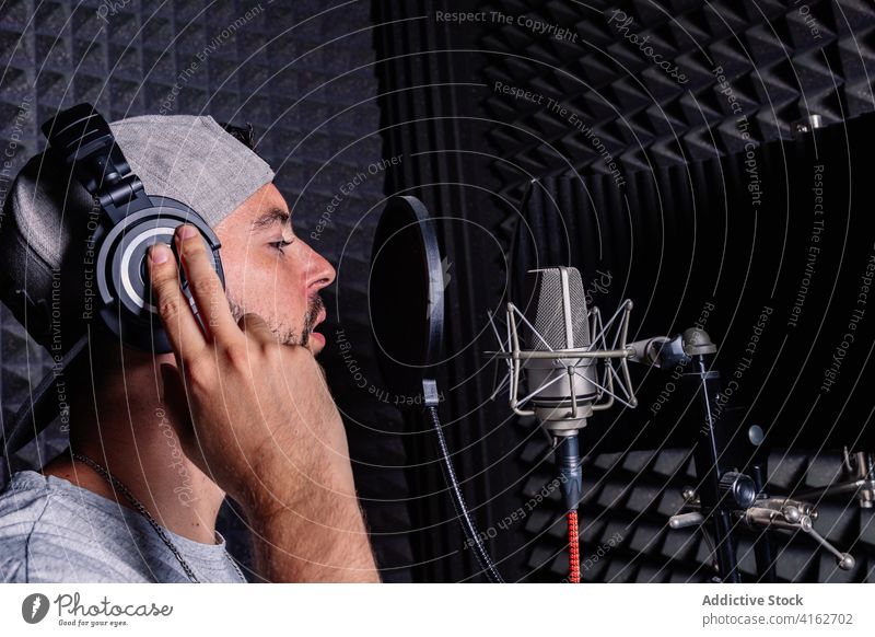 Man in recording studio microphone sing man artist hat singer headphones acoustic foam male sound proof song room music musician modern contemporary gadget cap