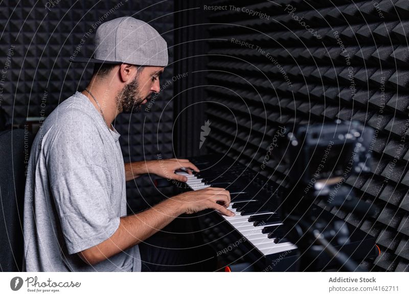 Man playing synthesizer in recording studio man sound proof foam video blogger male camera acoustic room equipment music professional hobby talent device art