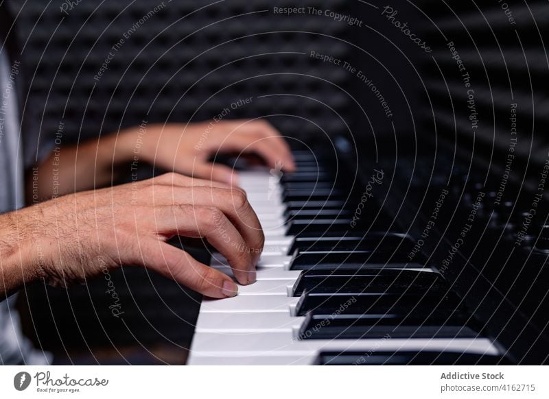 Anonymous man playing synthesizer in recording studio sound proof foam male acoustic room equipment music professional hobby talent device art artist guy