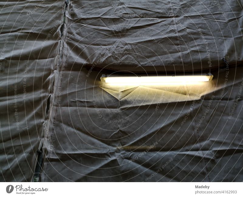 Black tarpaulin with slit for a burning light as protection at a building scaffold in the city centre of Bielefeld in the Teutoburg Forest in East Westphalia-Lippe