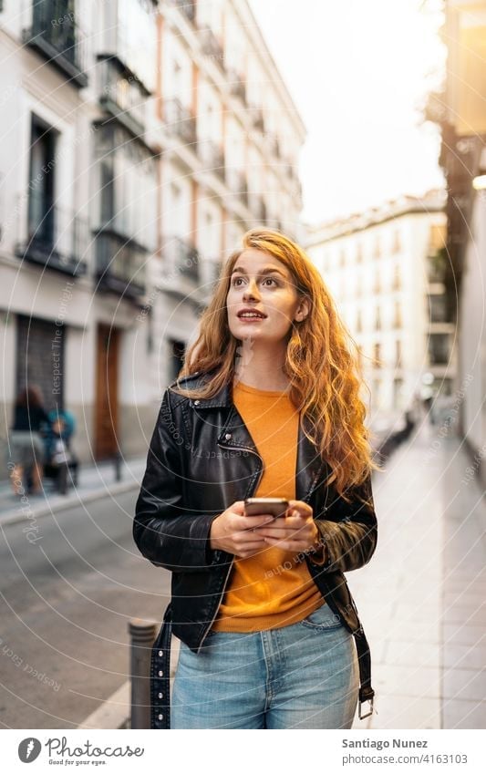 Ginger Head Woman Portrait portrait girl woman using phone ginger head pretty young street city front view outside typing cellphone looking smartphone