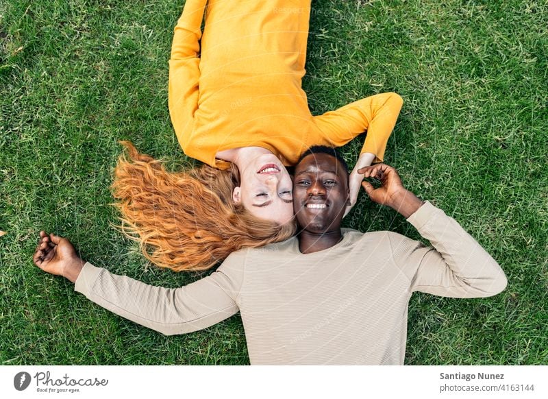 Multiethnic Couple Cuddling in the Grass lying grass having fun top view portrait relationship multi-racial black man caucasian multi-cultural multi-ethnic