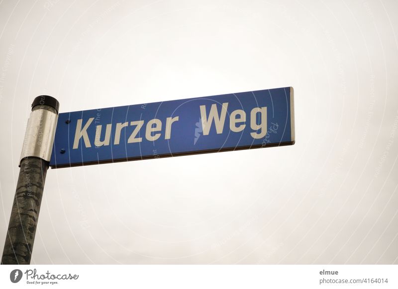 blue street sign " Kurzer Weg " at an iron bar / street name / live / bureaucracy short distance off Simple dwell symbolic long way Short route Clue Street