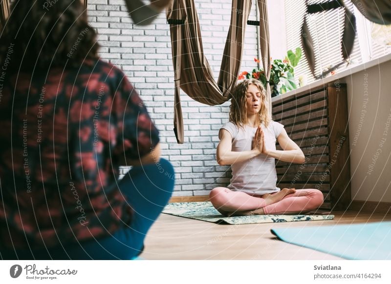 Two women sit on a mat in a yoga class and meditate after a workout. Rest, relaxation, meditation pose gym sporty practicing sitting lotus healthy lifestyle