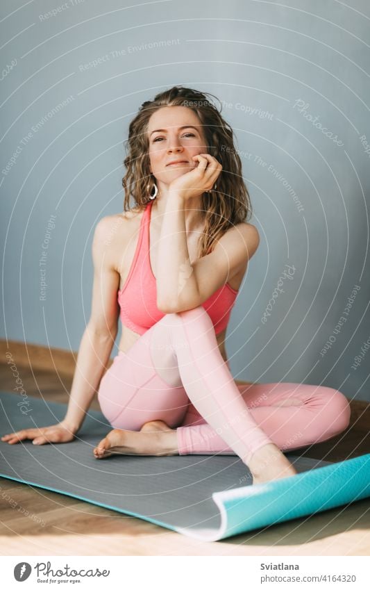 A young woman sits on a yoga mat and rests after a workout. Sports, fitness. Healthy lifestyle concept sitting beautiful girl healthy exercise finish