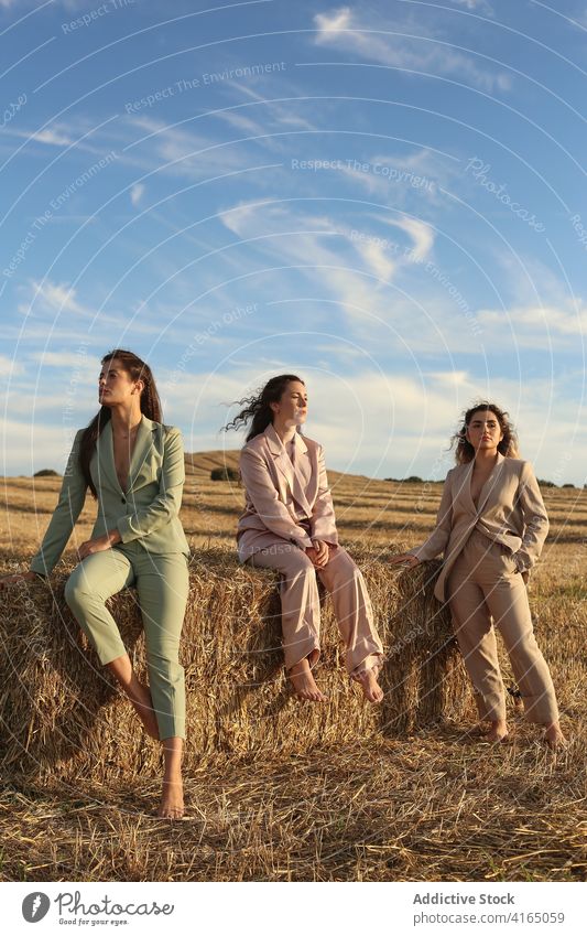 Stylish female friends standing on dry hay in field women haystack countryside model style together spend time trendy relax young relationship idyllic nature