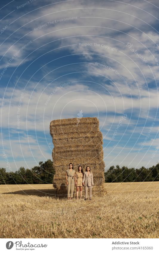 Stylish female friends standing on dry hay in field women haystack countryside model style together spend time trendy relax serene harmony rest tranquil young