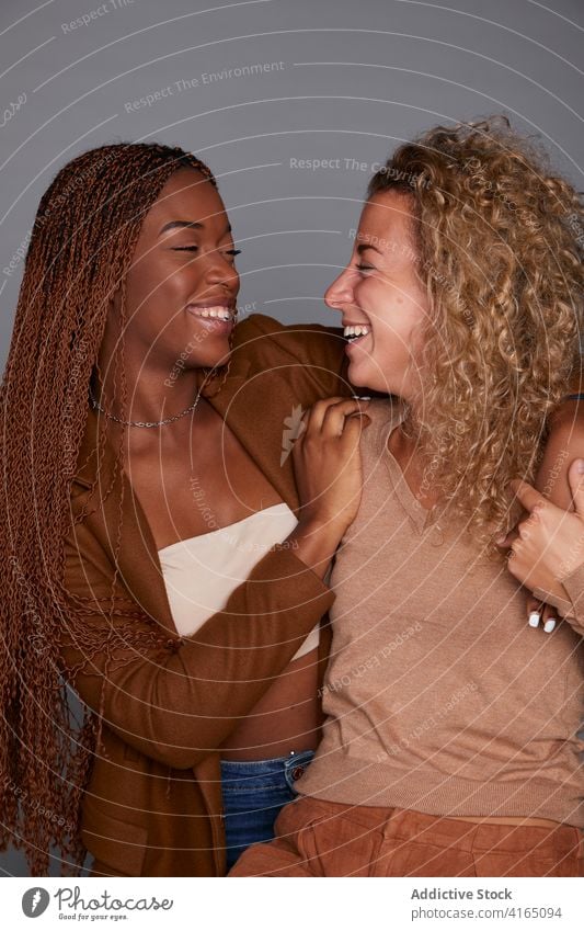 Cheerful multiethnic women laughing in studio friendship having fun joke humor cuddle best friend diverse multiracial black african american curly hair braid