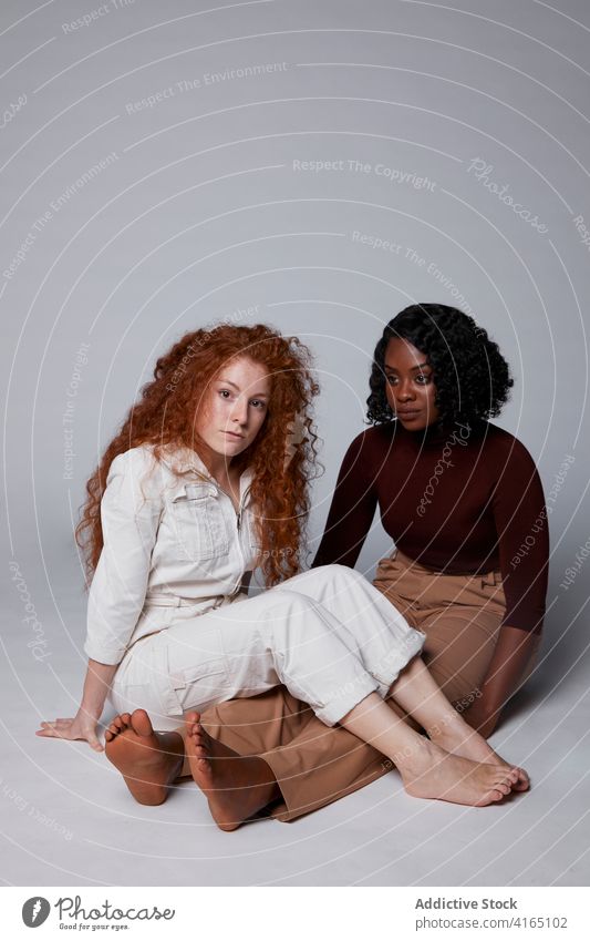 Multiethnic women sitting on gray background studio friend friendship together style casual delight multiethnic multiracial diverse black african american happy