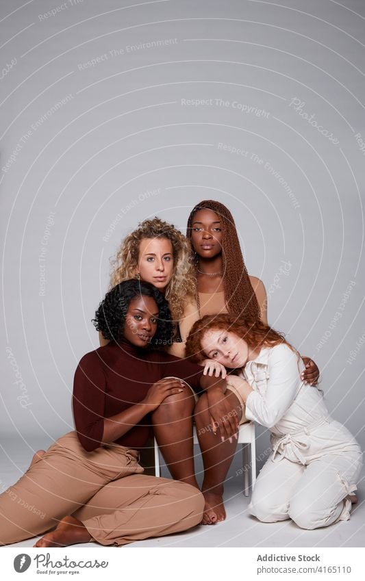 Multiethnic women gathering on gray background unity hug together friendship cuddle tender company multiethnic multiracial diverse black african american