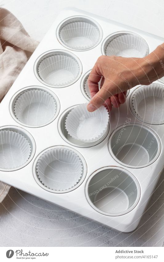 Crop unrecognizable man putting baking cups on muffin pan chef parchment bakery baking paper baking pan process prepare tool cook culinary kitchen male recipe