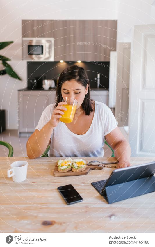 Woman drinking orange juice during healthy breakfast time indoors home house girl woman avocado shopping kitchen coffee morning caucasian brunette table