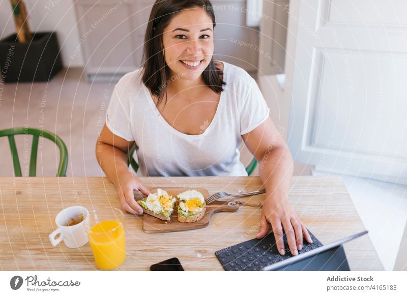 Happy and smiley woman having breakfast and working indoors home house girl avocado shopping kitchen coffee morning caucasian brunette table lifestyle casual