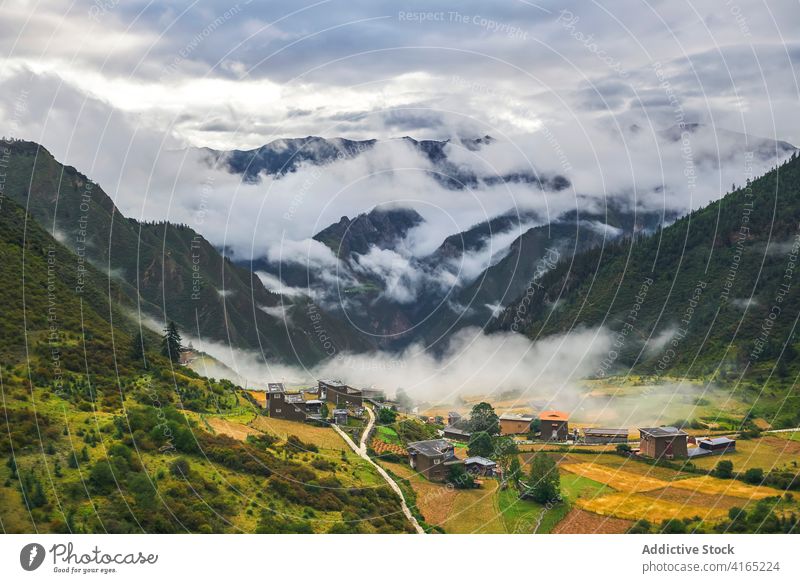 Small Asian village located among high mountains covered with clouds highland environment range cloudy altitude town nature landscape valley peak plant ridge