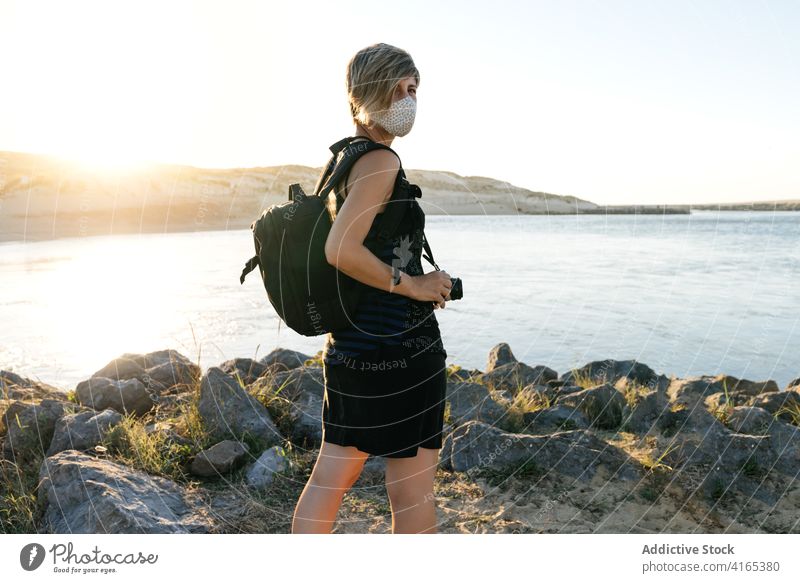 Anonymous lady admiring sea view from rocky coast at sunset woman seashore traveler admire recreation vacation journey new normal trip holiday relax female