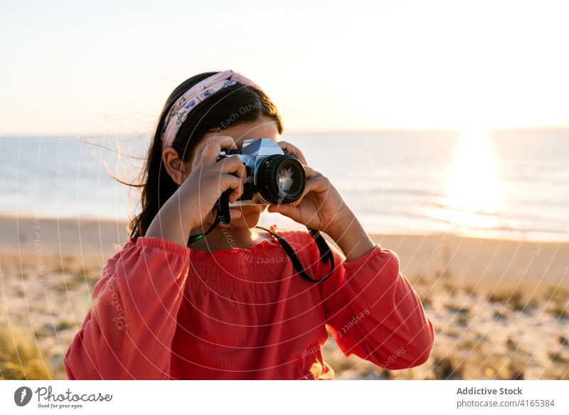Unrecognizable female teenager photographing sea at sunset girl take photo beach travel admire holiday coast sand shore nature style trendy trip seaside sundown