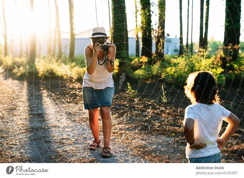 Anonymous mother taking photo of little boy in forest on sunny day woman take photo child park nature alley photographer travel son together summer vacation