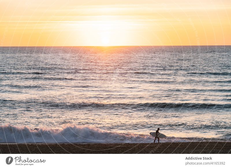 Silhouette of surfer walking on beach at sundown person ocean sunset surfboard wave sky vacation nature water activity extreme hobby sport sand recreation