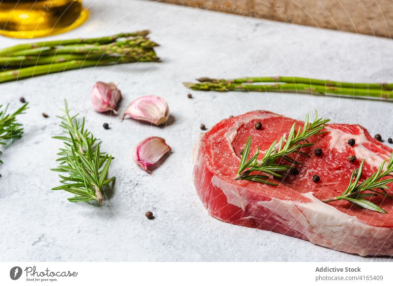 Raw beef steak with herbs on table raw bone t bone rosemary garnish meat pepper black kitchen cook food cuisine delicious dish spice gourmet fresh recipe sprig