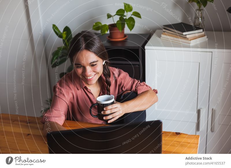 Cheerful woman with cup of coffee using laptop netbook happy browsing toothy smile cheerful smart watch surfing gadget contemporary modern device internet