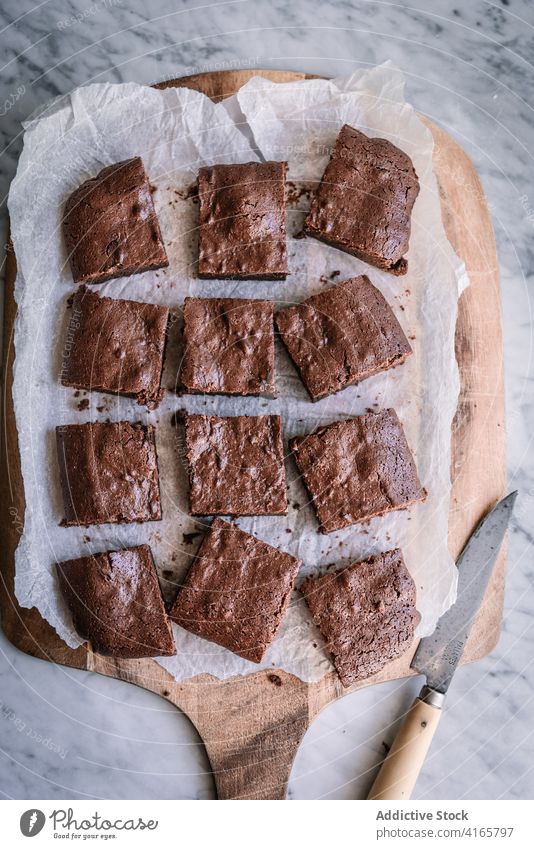 Tasty homemade brownies on parchment in kitchen piece dessert baked treat sweet tasty cutting board knife chocolate table natural slice product marble yummy