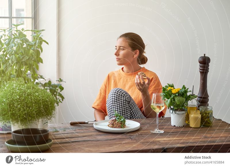 Pensive woman having tasty lunch at home steak tartare eat wine drink enjoy weekend dish delight female plate table smile rest happy gourmet healthy nutrition