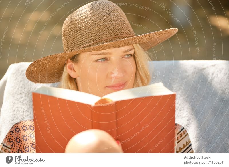 Cheerful female tourist reading book while resting on deckchair woman chill beautiful travel happy holiday relax resort lounge break vacation weekend summer