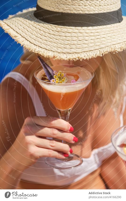 Unrecognizable blondie drinking refreshing cocktail near pool woman poolside holiday refreshment traveler style fashion relax exotic tropical beverage female