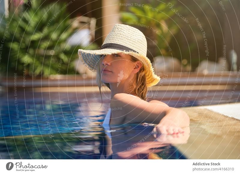 Sensual woman in hat relaxing in pool summer chill sensual poolside enjoy reflection young female resort vacation holiday travel rest recreation paradise
