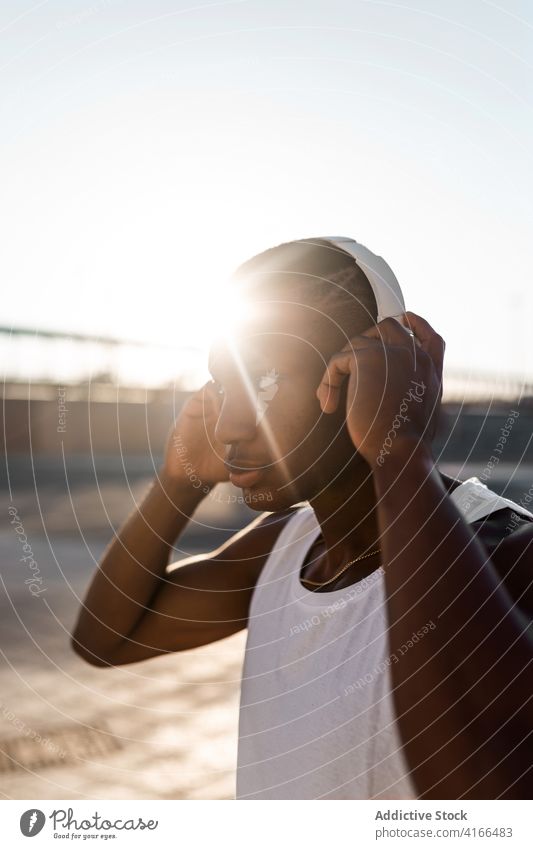 Black sportive man listening to music runner anonymous using headphones training athlete workout break sportsman gadget sportswear wireless lifestyle modern