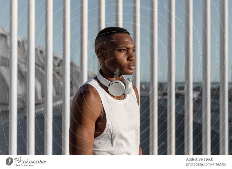 Confident black man standing near fence after training serious confident sport concentrate focus muscle strong sporty rest male muscular thoughtful sportsman