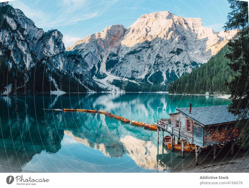 Wooden house and boats on lake in mountains turquoise water color wooden float reflection smooth surface calm clear shore scenery majestic morning light nature