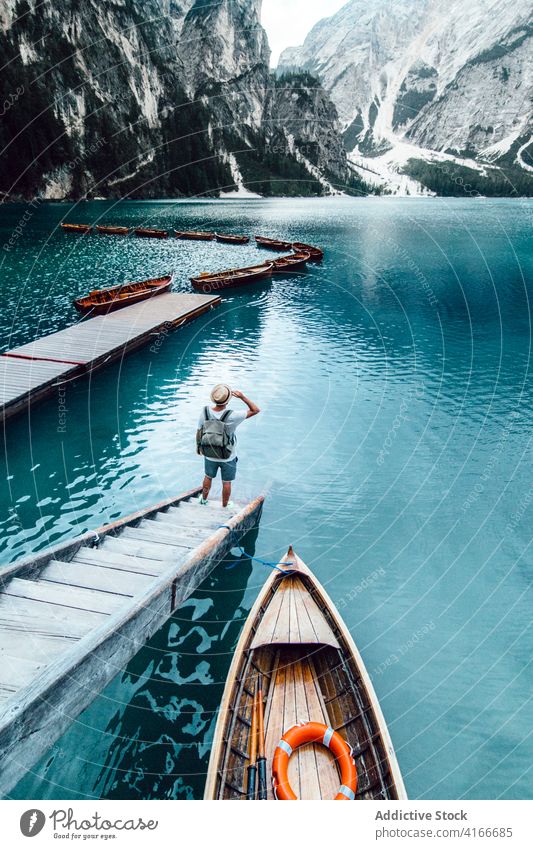 Traveling man on wooden pier near lake turquoise mountain travel adventure wanderlust landscape water male amazing traveler quay scenery vacation trip holiday