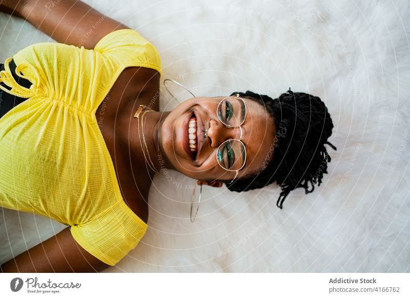 Young black woman relaxing at home lying on floor carpet rest free time weekend comfort cozy calm peaceful female young african american ethnic casual