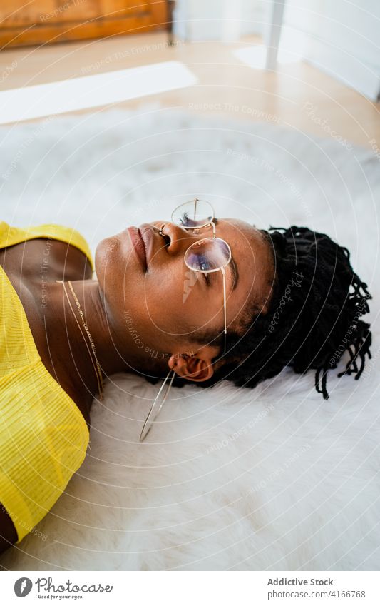 Young black woman relaxing at home lying on floor carpet rest free time weekend comfort cozy calm peaceful female young african american ethnic casual