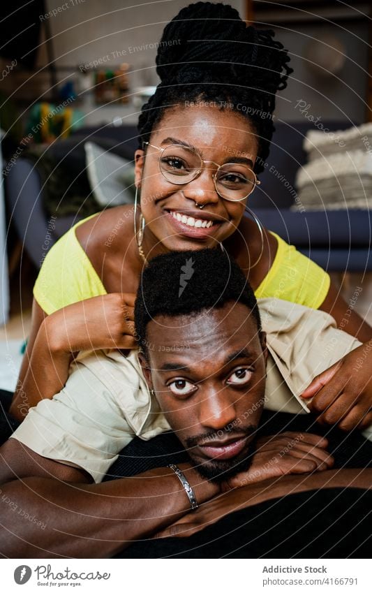 Cheerful young African American couple cuddling while lying on floor at home cuddle spend time together happy love romantic relax weekend relationship affection