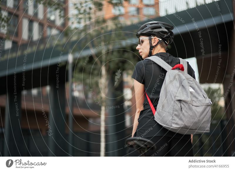 Woman cyclist with backpack outdoors on summer day Cyclist building brick city woman young sports riding helmet protective sunglasses girl delivery courier