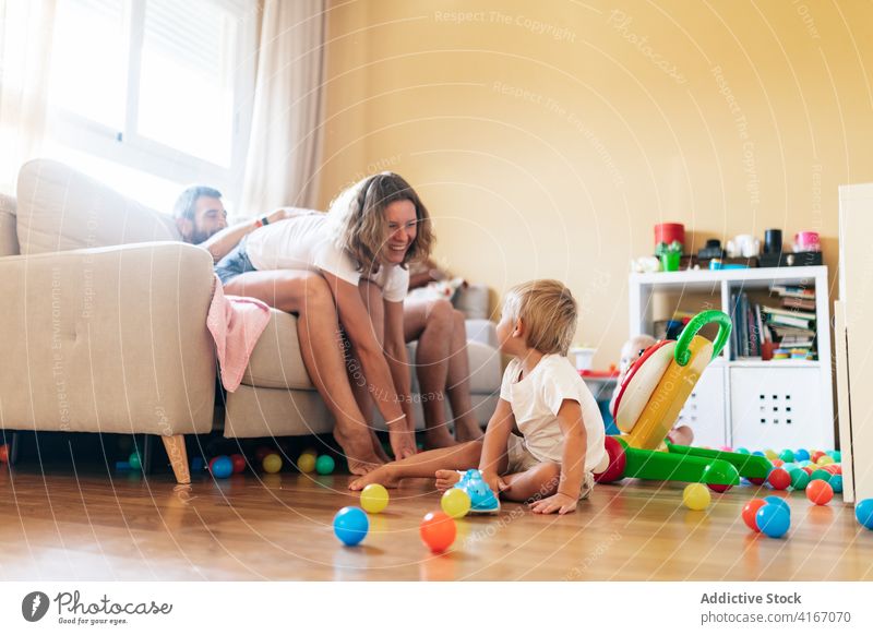 Happy mother playing with toddler family baby father cheerful happy fun sofa wife husband living room boy kid childhood parenthood affection joy motherhood
